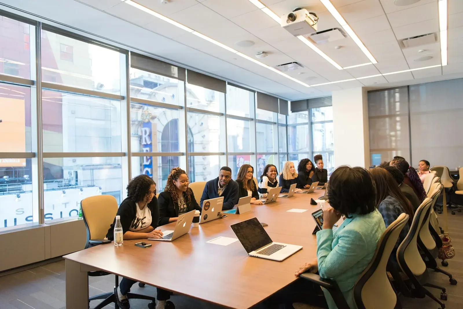 Colleagues working together with laptops around a long conference table