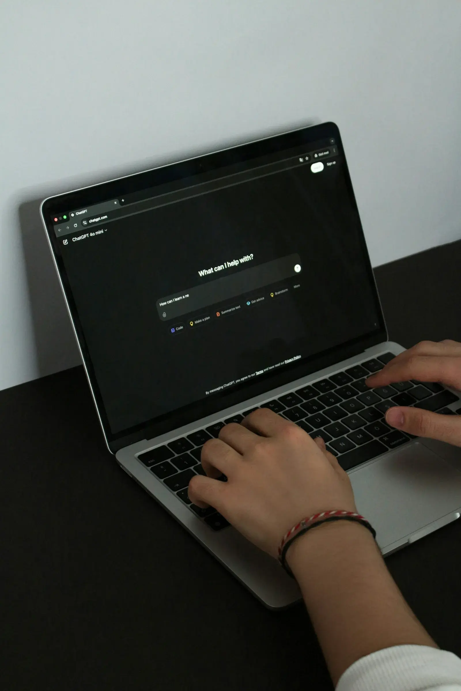 A person typing a prompt into ChatGPT on a laptop